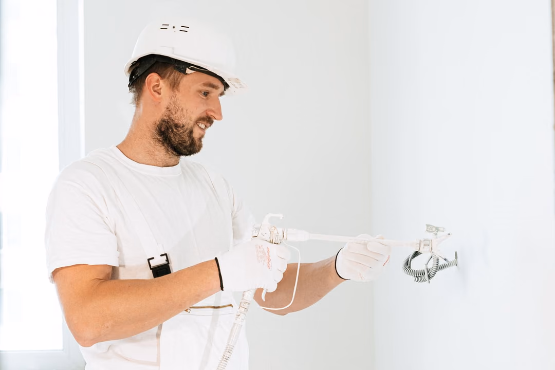 Ein Elektriker installiert eine Steckdose an einer weißen Wand
